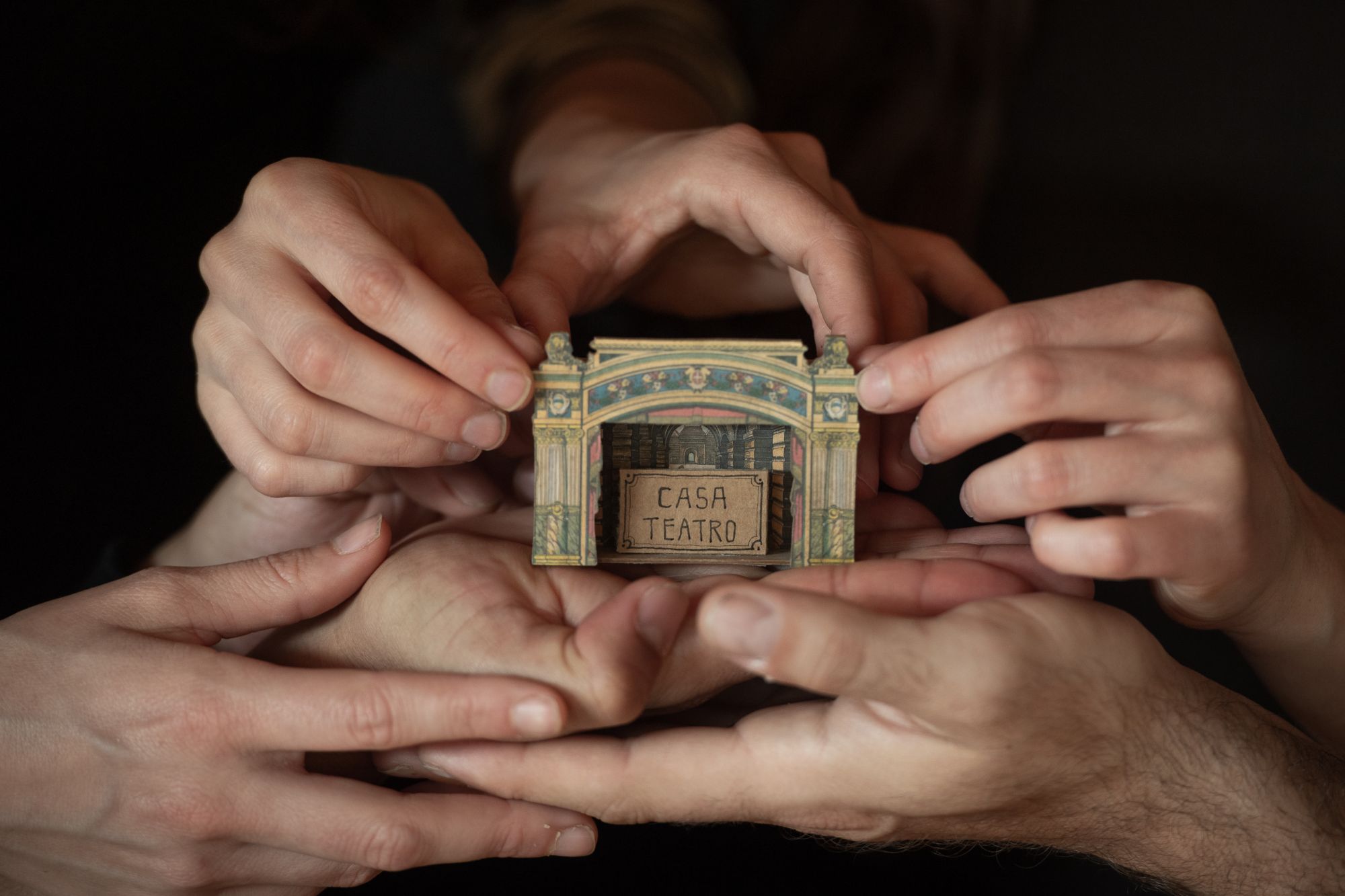 Image of hands with the house-Teatre between them